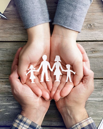 Hands holding a paper cut out of a family